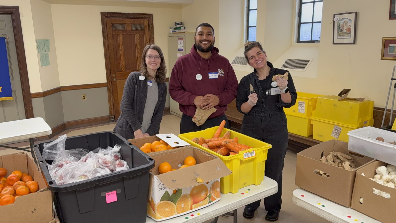 A volunteer handing a bag of fresh groceries to a neighbor on pantry day